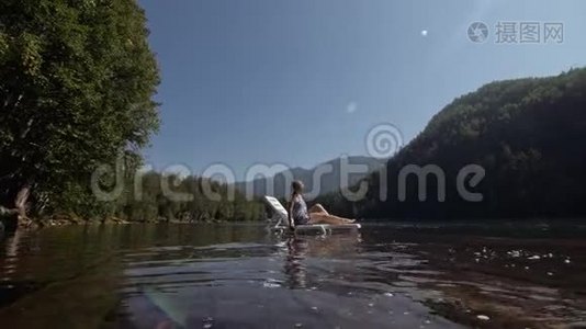 女人躺在日光浴床上，戴着太阳镜和一条薄纱披肩。 女孩在洪水木水下码头休息。 路面是视频