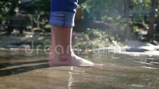 赤着脚的年轻女子在水流缓慢的溪流中溅起水花，踢着腿。 女士们享受假期视频