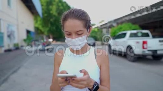 年轻女子戴着防护面罩站在街上，用手机视频