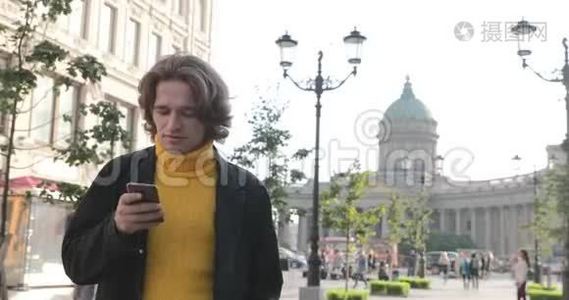 帅哥在等人，他穿着黄色的毛衣和黑色的雨衣，波什亚·科努申纳亚街视频