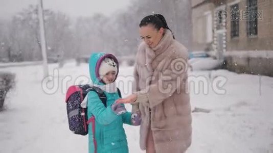 妈妈和女儿在冬天放学回家。视频