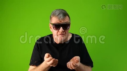 戴着黑墨镜的壮年男子愤怒地大声疾呼和咒骂，用双手在绿色上积极地打手势视频