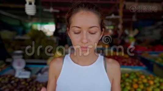 一个年轻的女人戴着防护面具，站在市场上看着摄像机视频