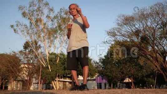 在阳光明媚的日子里，亚洲老人在公园里慢跑，以保持身体健康。 保健概念。视频