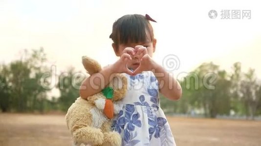 可爱的亚洲小女孩拥抱兔子娃娃与微笑的脸在公共公园。视频