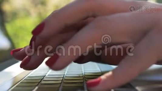 女性手在笔记本电脑键盘上输入一些文字。 在户外笔记本上工作的女人。 女孩和别人聊天或者视频