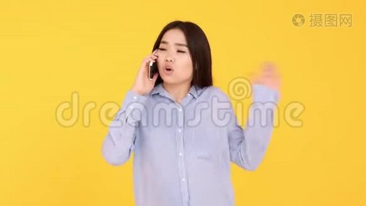 黄色背景的亚洲女孩在电话里交谈。 女人吵架，骂电话视频
