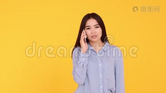 黄色背景的亚洲女孩在电话里交谈。 女人吵架，骂电话视频