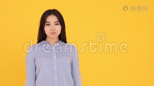 年轻的亚洲女孩对着镜头微笑。 复制空间黄色背景视频