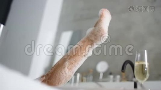 在泡沫浴缸里把女人的脚收起来。 不认识的女孩在浴缸里洗腿视频