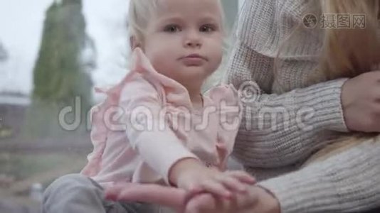 白人儿童拍手的肖像。 可爱的女婴坐在低矮的窗台上玩她视频