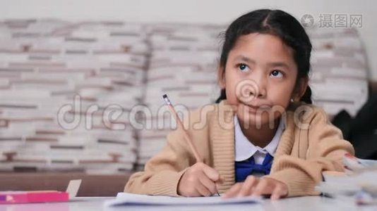 小亚洲女孩快乐地做作业，泰国女孩穿着学生幼儿园的制服，在家学习和教育视频