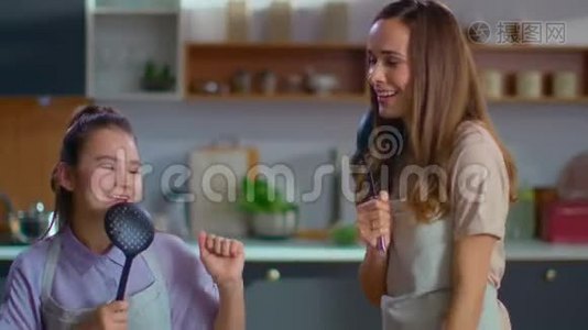 母女俩在厨房里用勺子唱歌。 家庭在家玩得开心视频