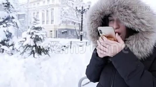 一个女人手里拿着一个电话，想在寒冷的冬天打出租车视频