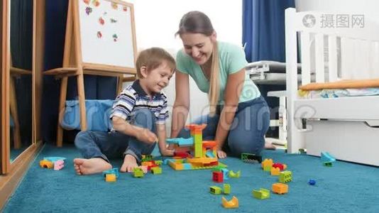 4k娃娃视频快乐的小男孩和年轻的母亲坐在地板上，建筑玩具大理石从五颜六色的建筑奔跑视频