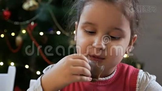 圣诞前夜坐在圣诞树旁吃巧克力圣诞老人的女孩。 在家庆祝圣诞节视频
