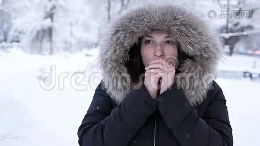 冬天的女孩吹在她的手上，寒冷的天气。 雪。 霜冻，冻僵，少女在冬季公园散步视频