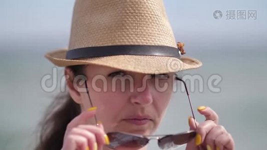 一个戴帽子的女人的特写照片戴上太阳镜看着镜头视频