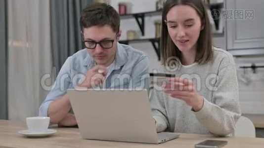 年轻夫妇在客厅的笔记本电脑上在线付款视频