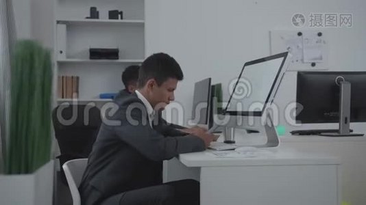 两个人坐在办公室的一张桌子旁。视频