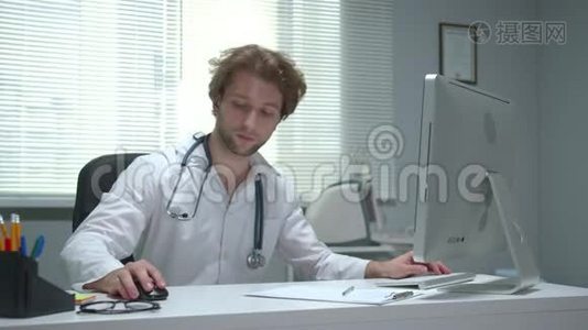医生坐在医院的一张桌子旁，用键盘打字视频