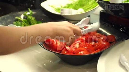 一个带钳子的女孩的特写需要一个切片的西红柿。 提供餐饮自助餐。视频