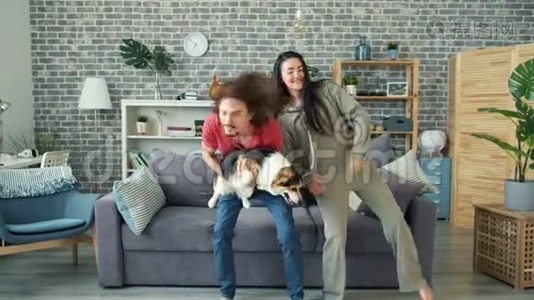 快乐的男人和女友一起跳舞，抱着科吉小狗，在家玩得很开心视频