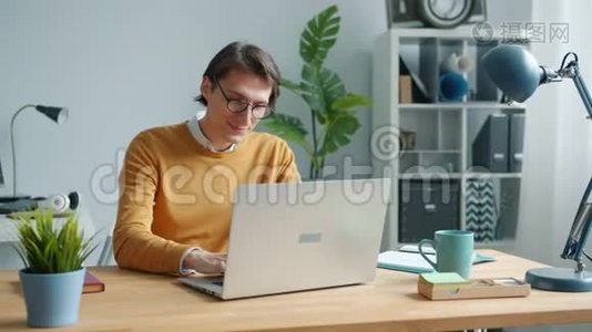 开朗的家伙用笔记本电脑打字在办公室的桌子上专心工作视频