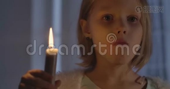 小白种人女孩举着蜡烛摇头的特写脸。 一个被什么东西吓倒的孩子的画像视频
