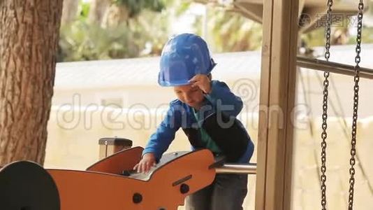 戴头盔的小男孩在操场上玩建筑工视频