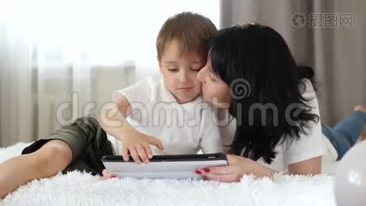 一个女人和一个小男孩用平板电脑打电话，看电影，上网。 对小工具的依赖。视频