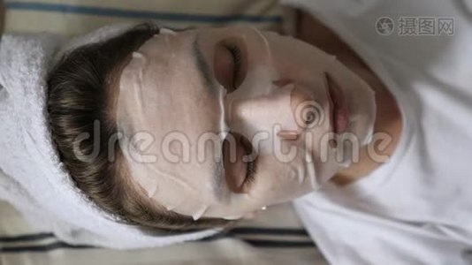 美丽和面部护理-一个戴着白色清洁面罩的女孩在工作日前休息，躺在上面视频