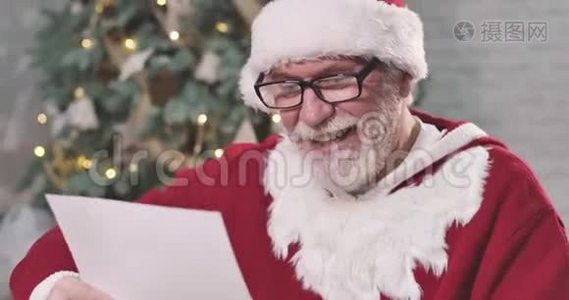 特写圣诞老人的肖像，戴着优雅的眼镜，读着信，挠着头。 圣诞老人在考虑礼物视频