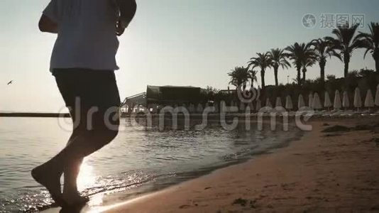 日落时分，一个人在海滩上奔跑的剪影。 积极健康的生活方式理念..视频