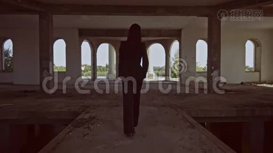 从后景中，黑发女人走进被遗弃的建筑视频