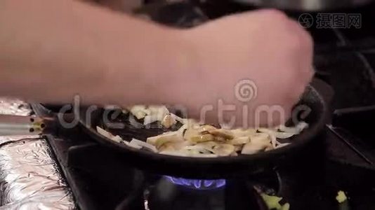 厨师在一个铸铁煎锅里把蘑菇和洋葱调羹。视频
