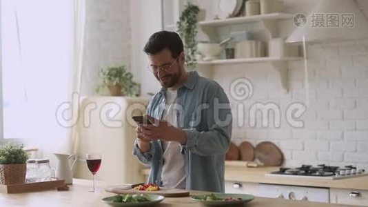 快乐的年轻人用智能手机应用程序准备浪漫晚餐视频
