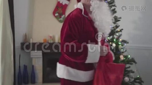 无法辨认的白人圣诞老人拿着他的礼品袋在圣诞树前跳舞。 节日快乐的概念视频