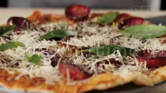专业厨师将新鲜的绿色罗勒叶放在意大利腊肠比萨饼上，以提高口味。 烹饪美味披萨的概念视频