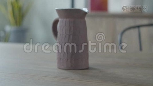 女性手把带苔藓的锅放在木桌上，陶瓷茶壶放在简约的室内公寓里。视频