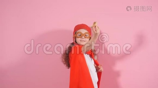漂亮的女孩穿着红色斗篷，戴着飞行员头盔，举起双手，手持木制玩具飞机视频