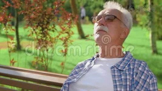 祖父坐在长凳上等着孙子们在公园玩耍视频