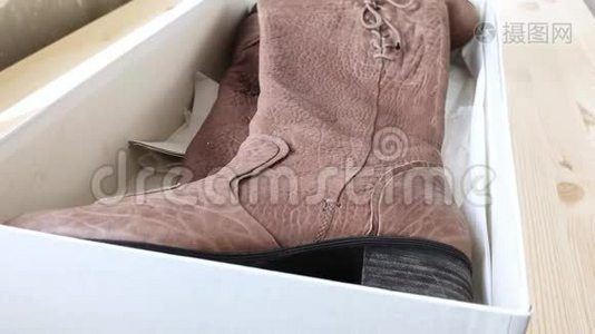 棕色女人`靴子躺在白色的盒子里。 鞋跟皮鞋脱箱，小规格的灰尘飞扬.. 侧视。 附件，视频