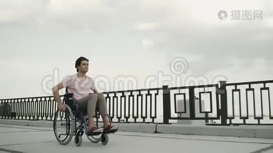 那个残废的人坐在轮椅上沿着堤岸骑马视频