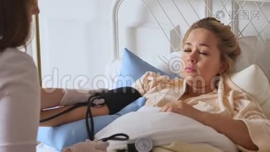 一位穿着白色外套的医生在床上休息时在家咨询一位妇女。 私人医生。 保健概念视频
