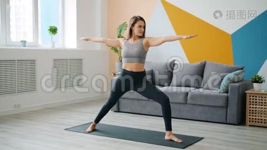 可爱的年轻女士在家里做运动，练习瑜伽垫，专注于活动视频