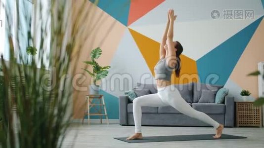 穿运动服装的无忧无虑的女孩独自在家做瑜伽体式视频