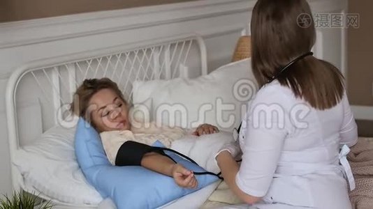 一位穿着白色外套的医生在床上休息时在家咨询一位妇女。 私人医生。 保健概念视频