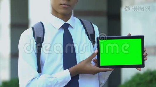 学生展示带有绿色屏幕的平板电脑，为电子书图书馆应用程序做广告视频