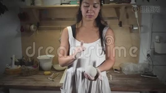 穿着白色围裙的亚洲女人用手臂揉着灰色粘土视频